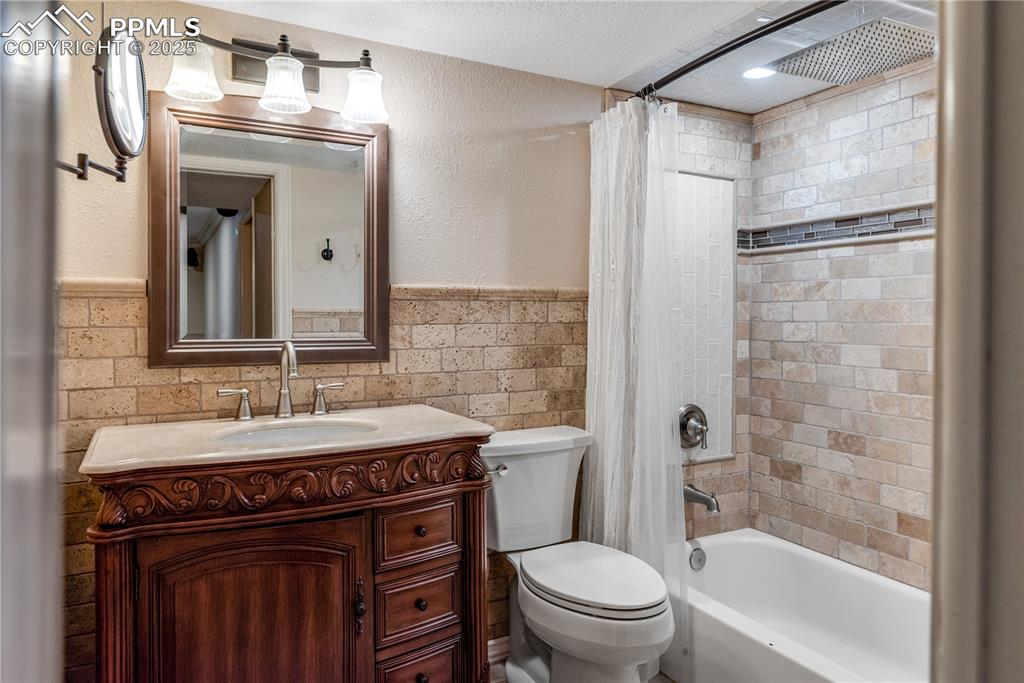 Image 27 of 46: Full bath with vanity, wainscoting, shower / bath combination with curtain,