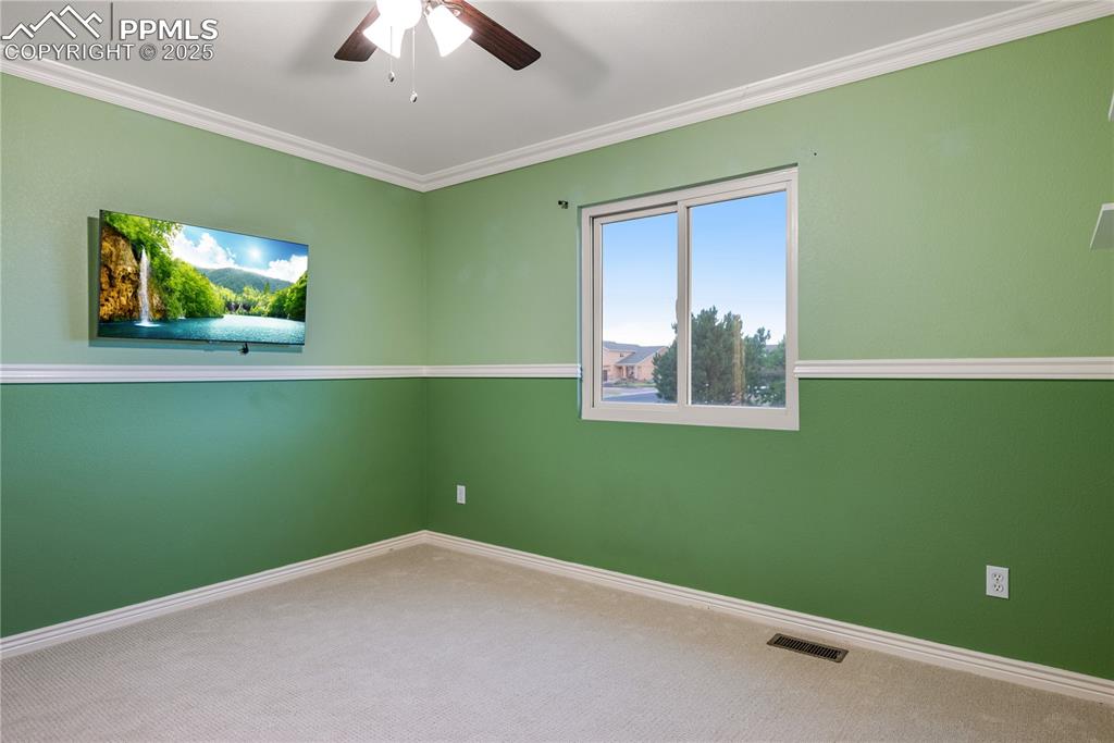 Image 38 of 46: Carpeted empty room featuring a ceiling fan and crown molding