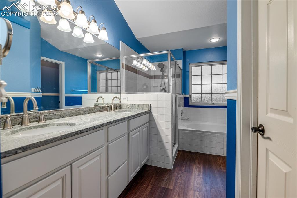 Image 41 of 46: Bathroom featuring a stall shower, double vanity, a garden tub, and wood fi