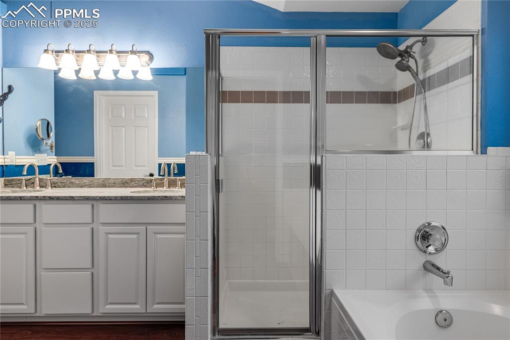 Image 43 of 46: Full bathroom featuring a shower stall, a bath, and double vanity