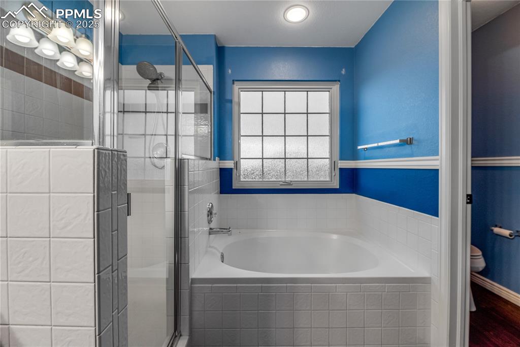 Image 44 of 46: Bathroom with a bath, a stall shower, and wood finished floors