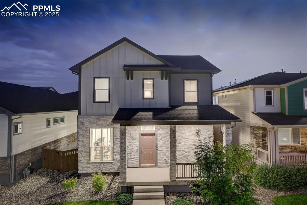 Caption: View of front of home featuring stone siding, board and batten siding, and a porch