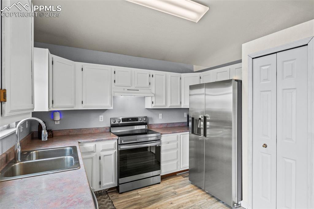 Image 11 of 35: Kitchen with stainless steel appliances, light wood-type flooring, white ca
