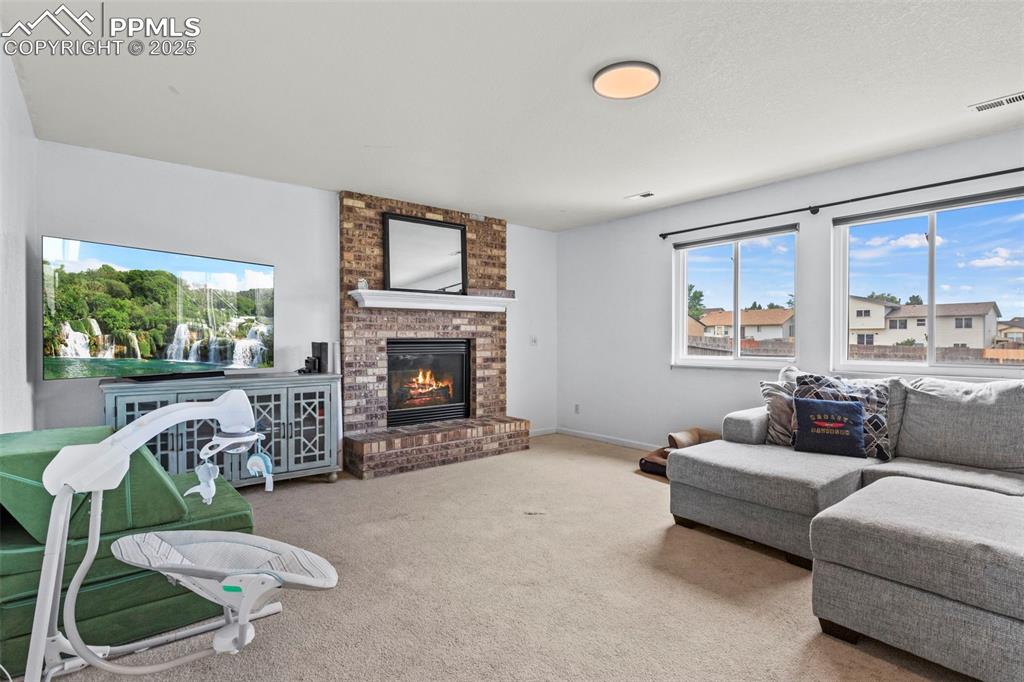 Image 15 of 35: Living area with carpet flooring and a brick fireplace