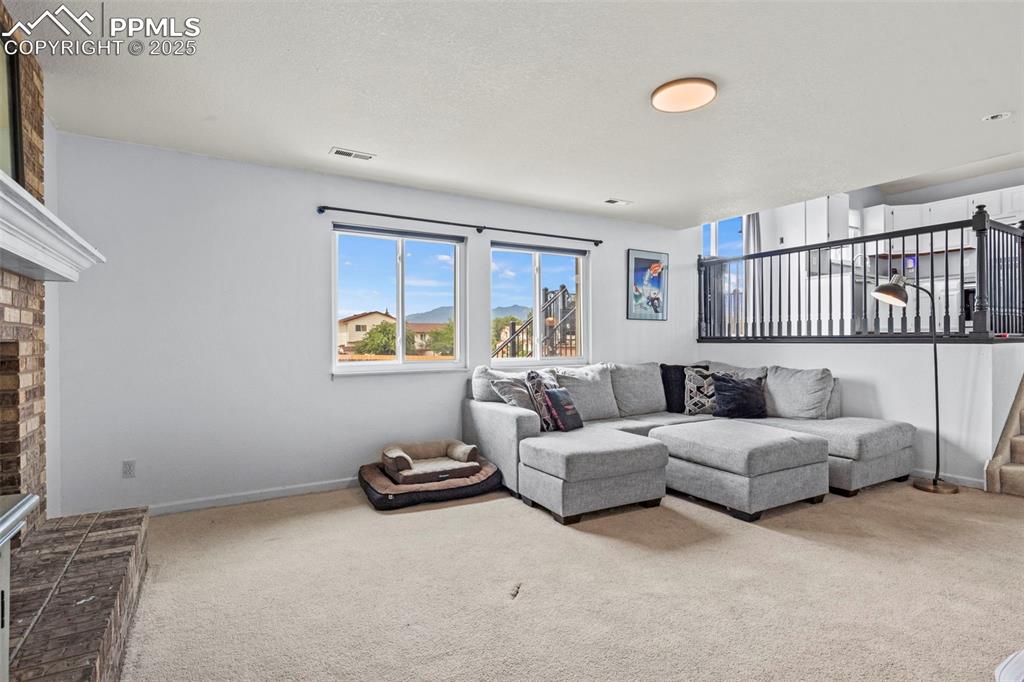 Image 17 of 35: Living room featuring carpet, a brick fireplace, and a textured ceiling