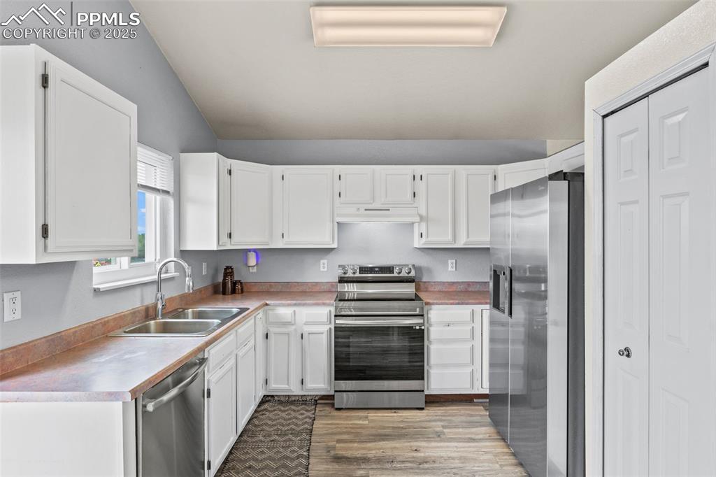 Image 2 of 35: Kitchen with appliances with stainless steel finishes, wood finished floors
