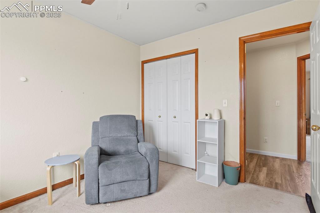 Image 27 of 35: Living area with light carpet and ceiling fan