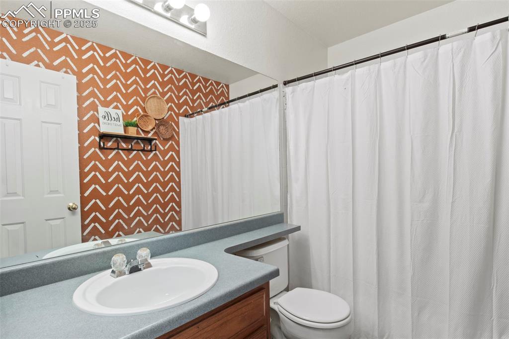 Image 28 of 35: Bathroom with vanity, wallpapered walls, and a shower with shower curtain