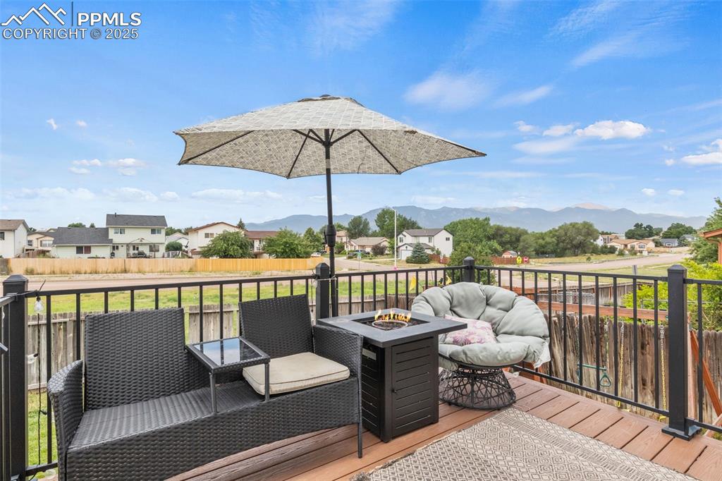 Image 3 of 35: Wooden deck featuring a fire pit, a residential view, and a mountain view