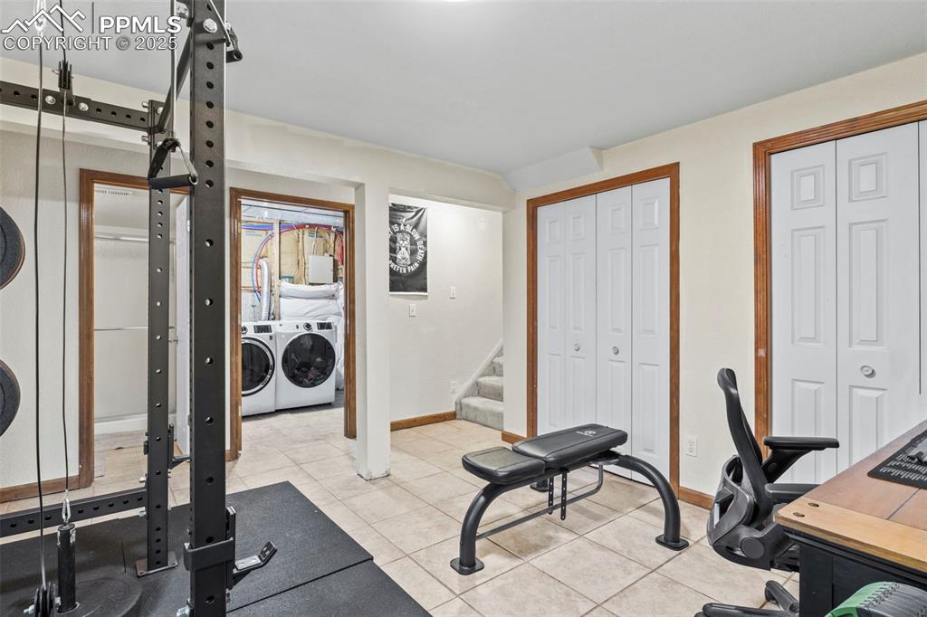 Image 30 of 35: Workout area featuring washing machine and dryer and light tile patterned f