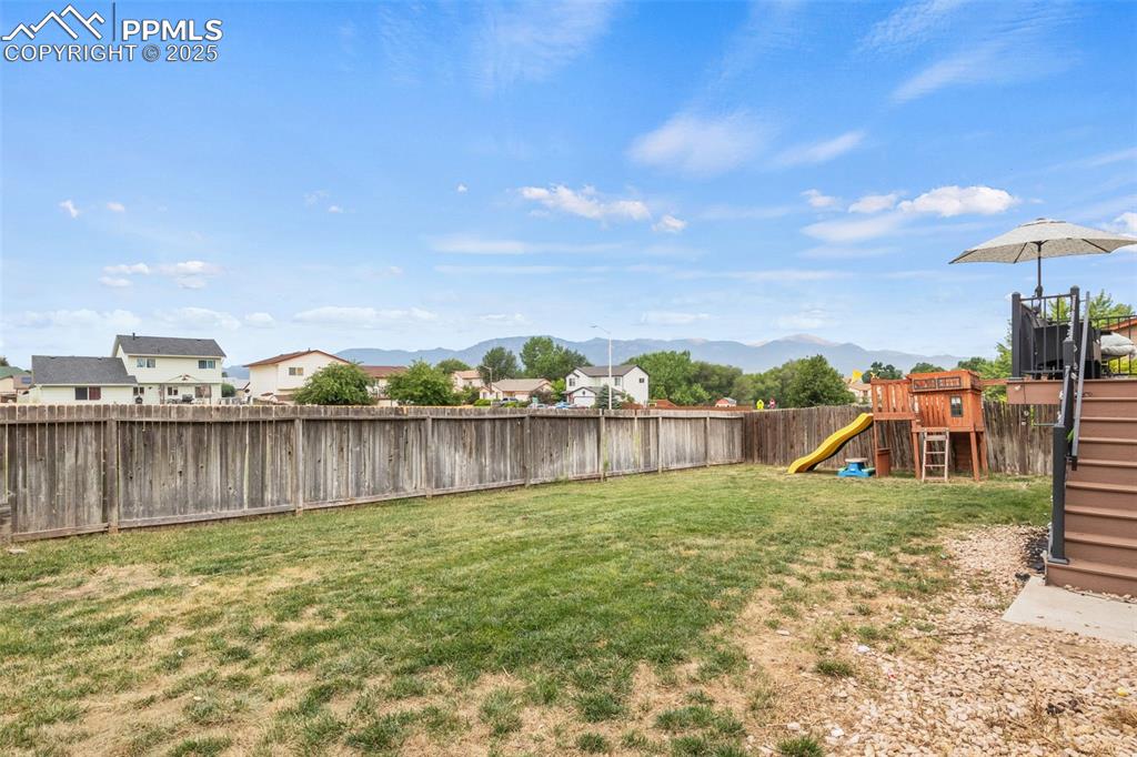 Image 33 of 35: Fenced backyard with a playground, a mountain view, and a residential view