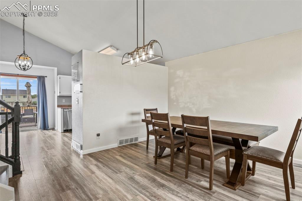 Image 6 of 35: Dining room with a chandelier, wood finished floors, stairs, and high vault