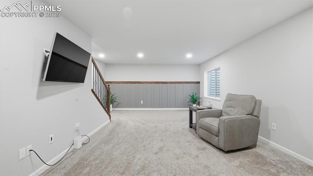 Image 25 of 42: Basement family room with neutral carpet and accented by decorative wainsco