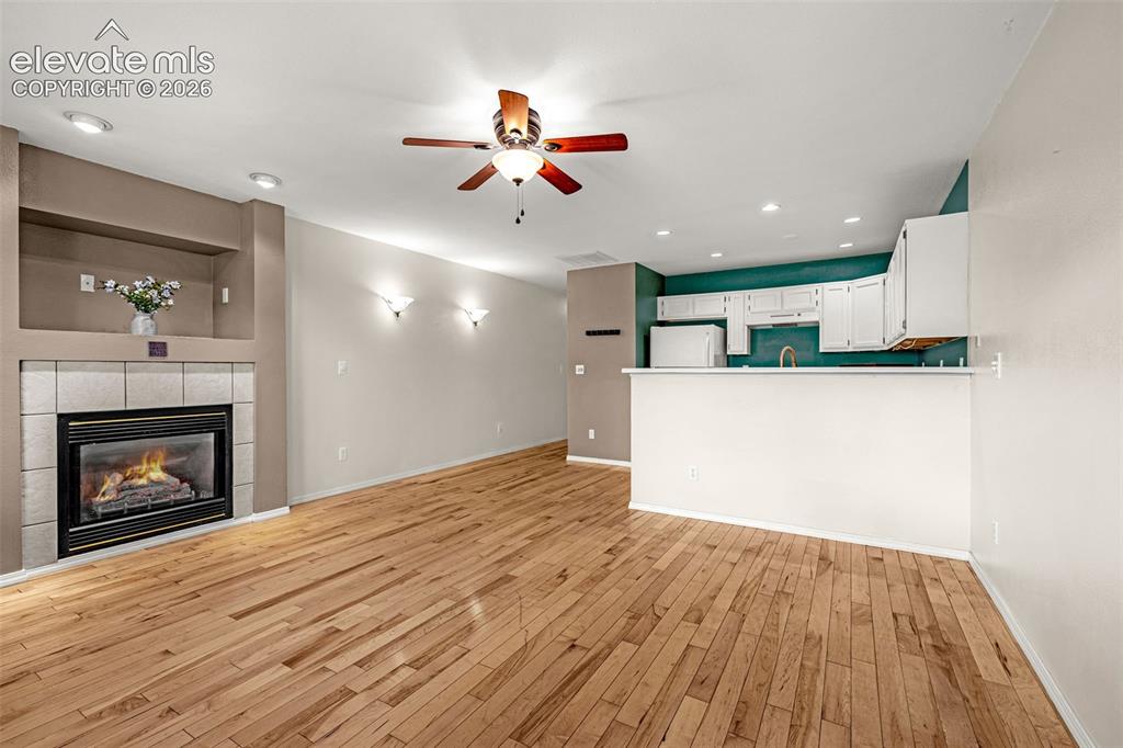 Image 2 of 15: Open concept living space featuring hardwood flooring, a tiled fireplace wi