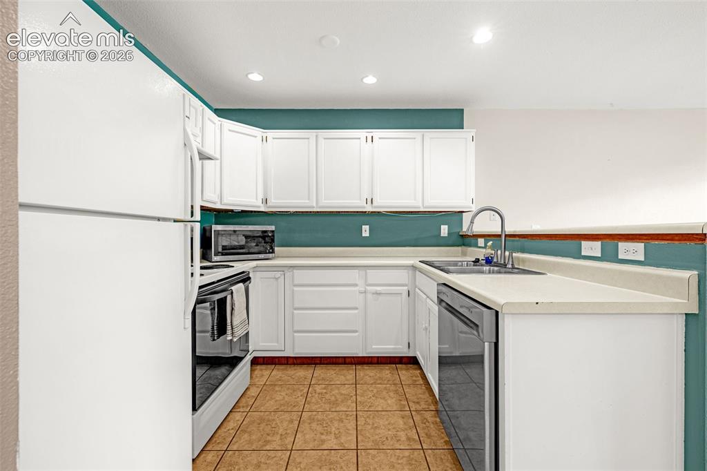 Image 3 of 15: U-shaped kitchen featuring white cabinetry, light-toned countertops, and ce