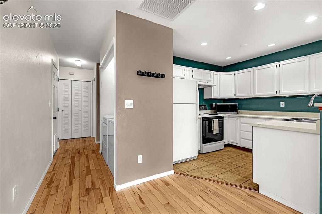Image 4 of 15: Kitchen with white cabinetry, light countertops, and a vibrant teal backspl