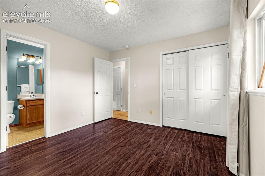Image 8 of 15: Bedoom featuring dark wood-finish flooring, light-toned walls, and a window