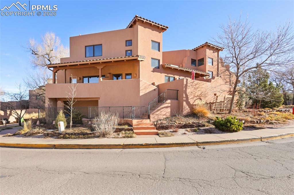 Image 1 of 19: View of front of home with stucco siding, a tiled roof, and a balcony
