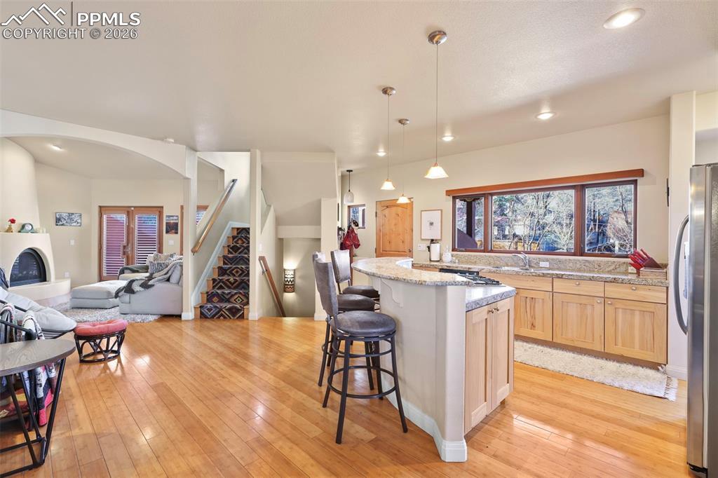 Image 6 of 19: Kitchen with light wood finish cabinetry, open floor plan, a breakfast bar 