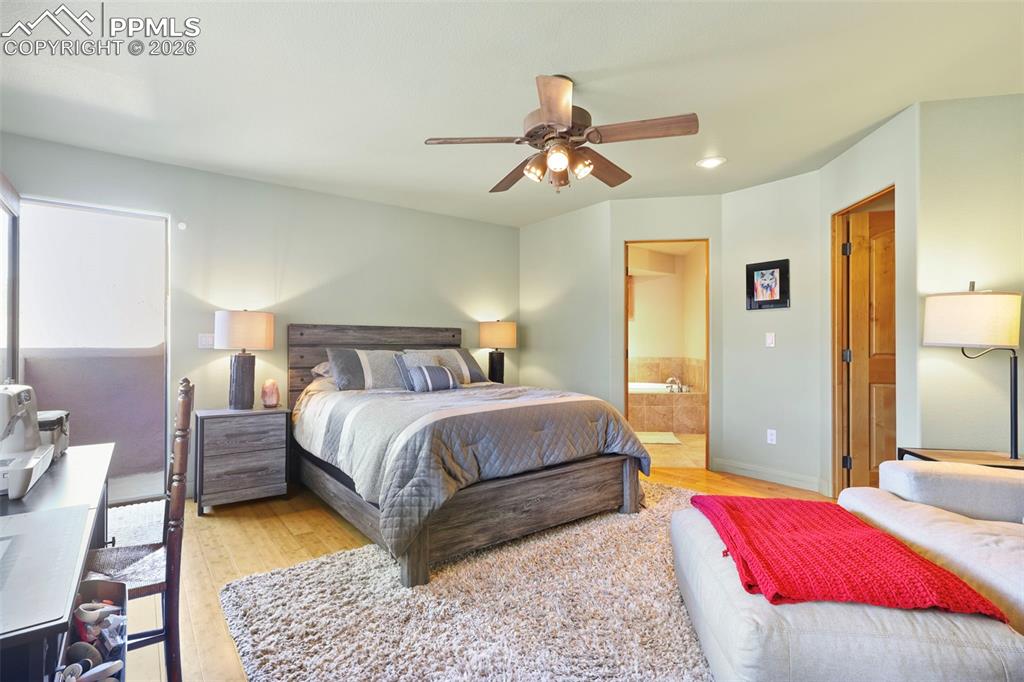 Image 8 of 19: Bedroom with connected bathroom, light wood finished floors, ceiling fan, a