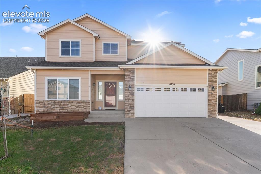 Caption: Two-story residence featuring light-colored siding and stone veneer accents