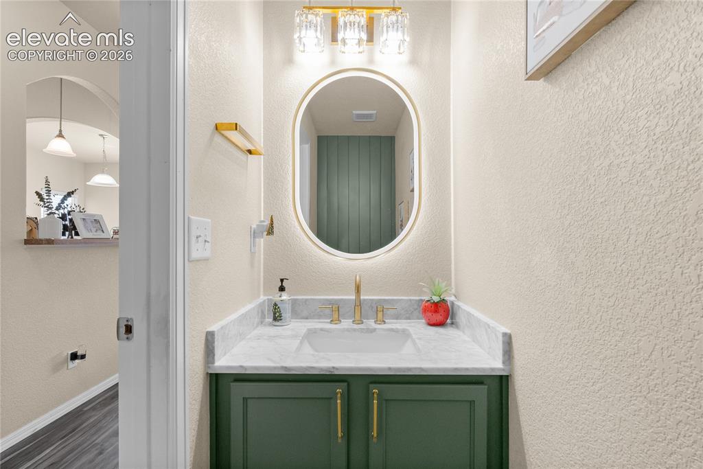 Image 10 of 41: Bathroom vanity featuring a green base cabinet with gold-toned hardware, a 