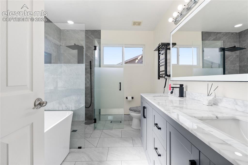 Image 15 of 41: Spacious bathroom featuring a freestanding tub, glass-enclosed shower with 