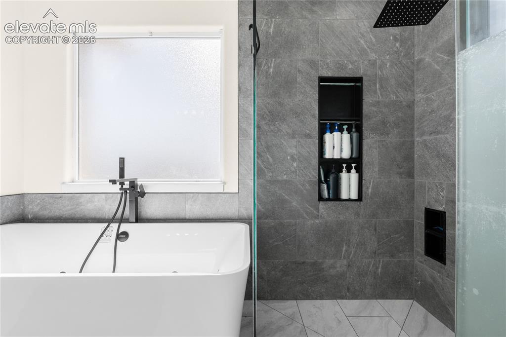 Image 16 of 41: Contemporary bathroom featuring a freestanding soaking tub with a matte bla