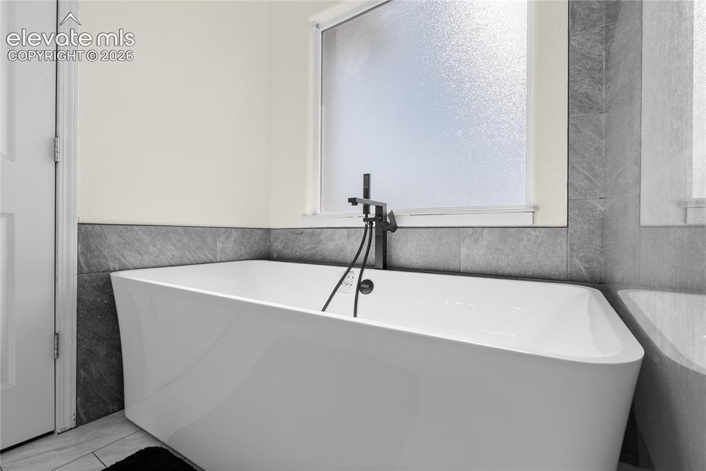 Image 17 of 41: Freestanding white soaking tub with a modern black floor-mounted faucet