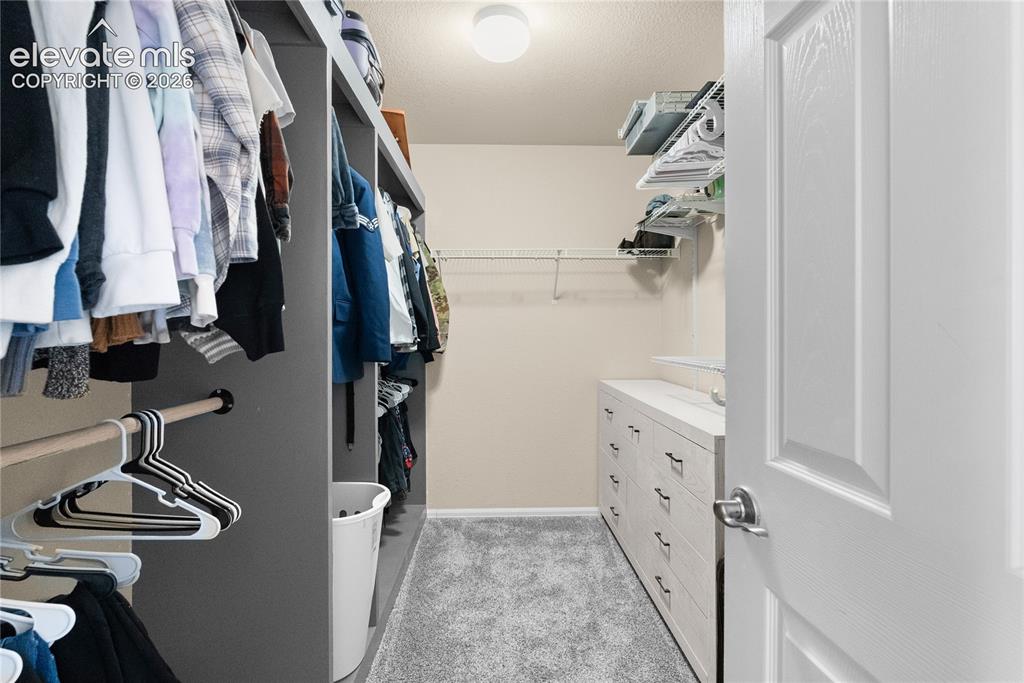 Image 21 of 41: Walk-in closet featuring built-in shelving, hanging rods, an integrated dre