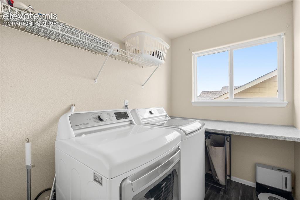 Image 23 of 41: Dedicated laundry room featuring wood-finish flooring, a white window, and 