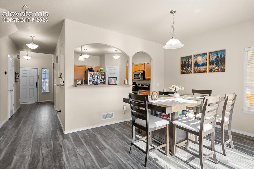 Image 3 of 41: Expansive dining area with wood-finish flooring, featuring an arched passth