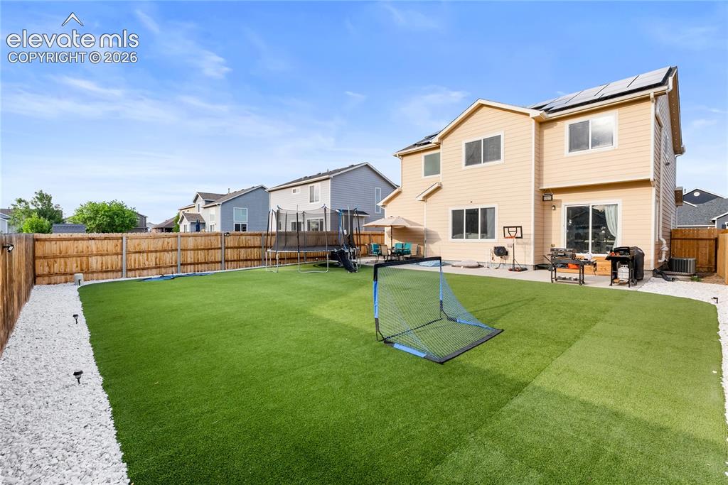 Image 31 of 41: Spacious backyard featuring artificial turf, a concrete patio, and a wood p