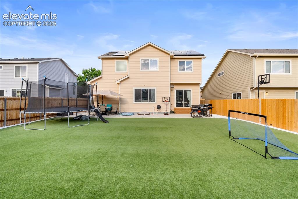 Image 33 of 41: Expansive backyard featuring artificial turf, a concrete patio, and a woode