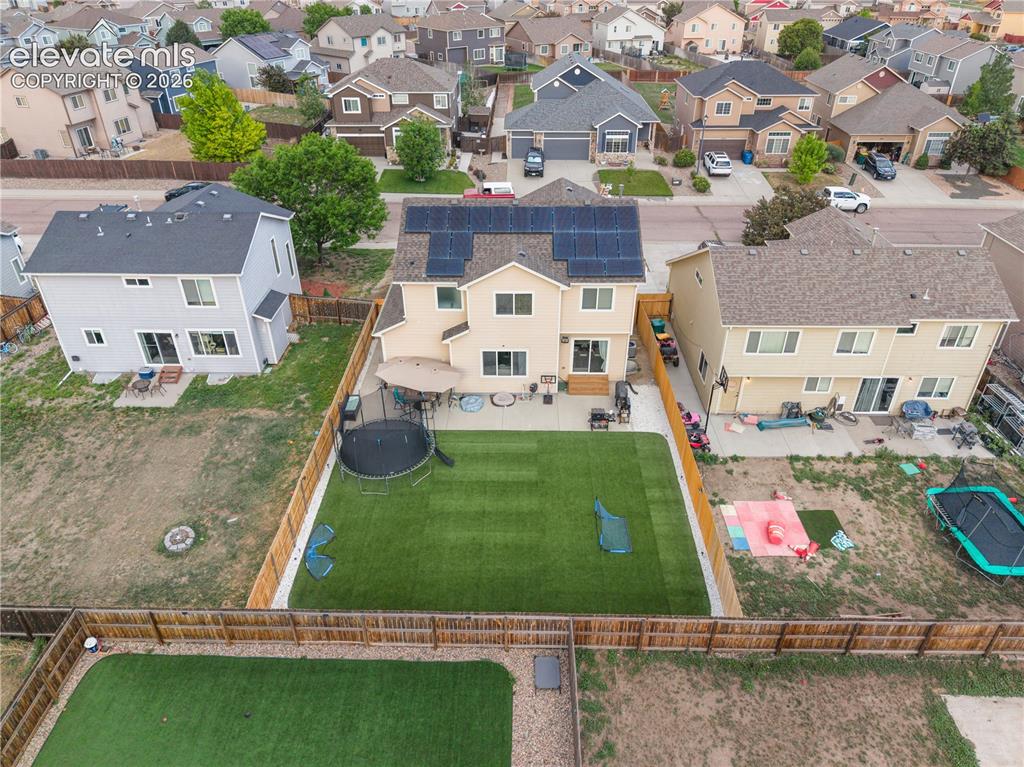 Image 35 of 41: Rear exterior featuring solar panels, a fenced yard, and a patio with outdo