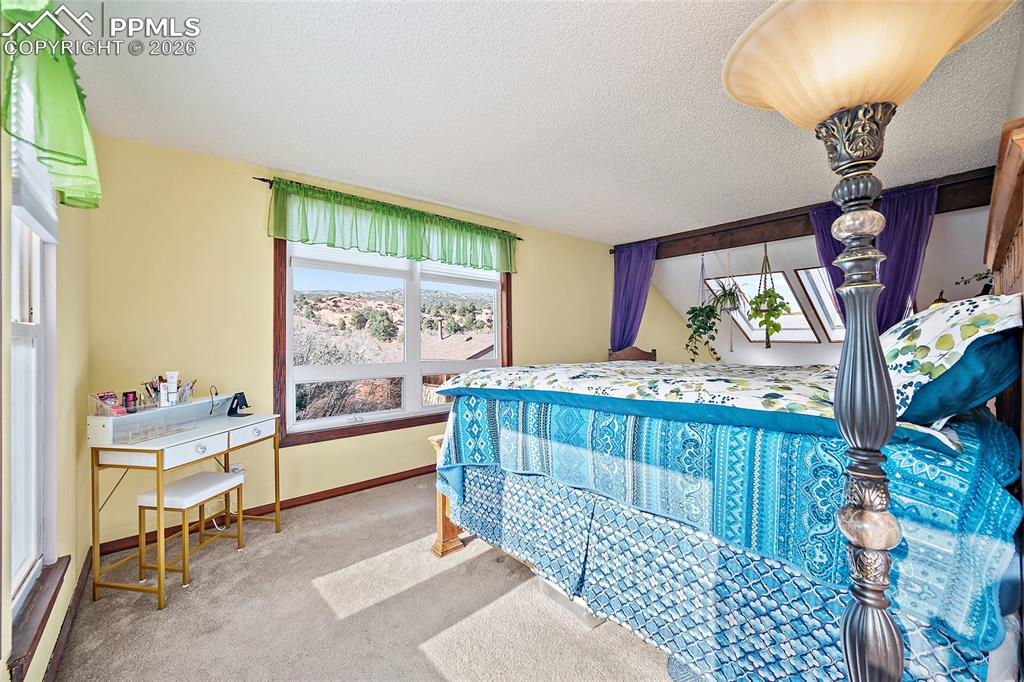 Image 17 of 32: Master bedroom with a view of window and red rocks outside. Skylights off t
