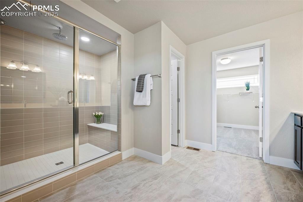 Image 22 of 41: Spacious shower with bench and upgraded tile, separate toilet area and walk
