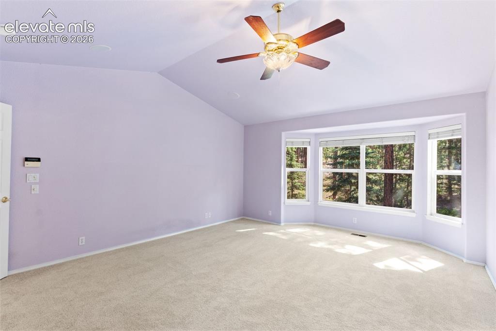 Image 10 of 50: Primary bedroom with vaulted ceiling, ceiling fan, ensuite bathroom, and wa