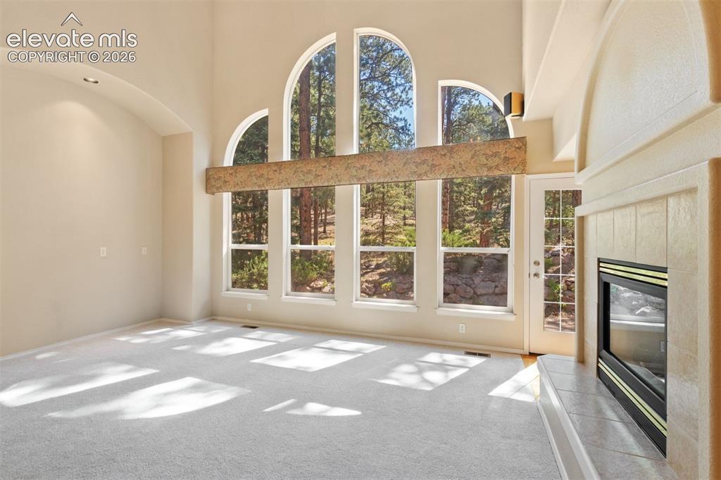 Image 15 of 50: Family room with dual sided fireplace and wall of windows