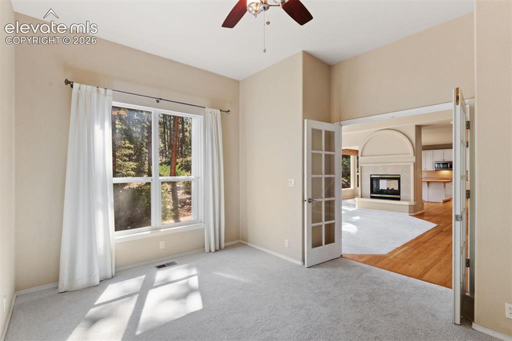 Image 18 of 50: Dedicated main level office with french doors and ceiling fan
