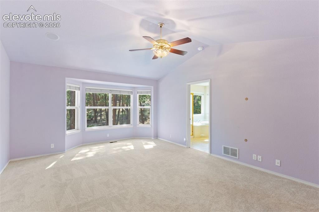 Image 26 of 50: Primary bedroom with vaulted ceiling, french doors, ceiling fan, and ensuit