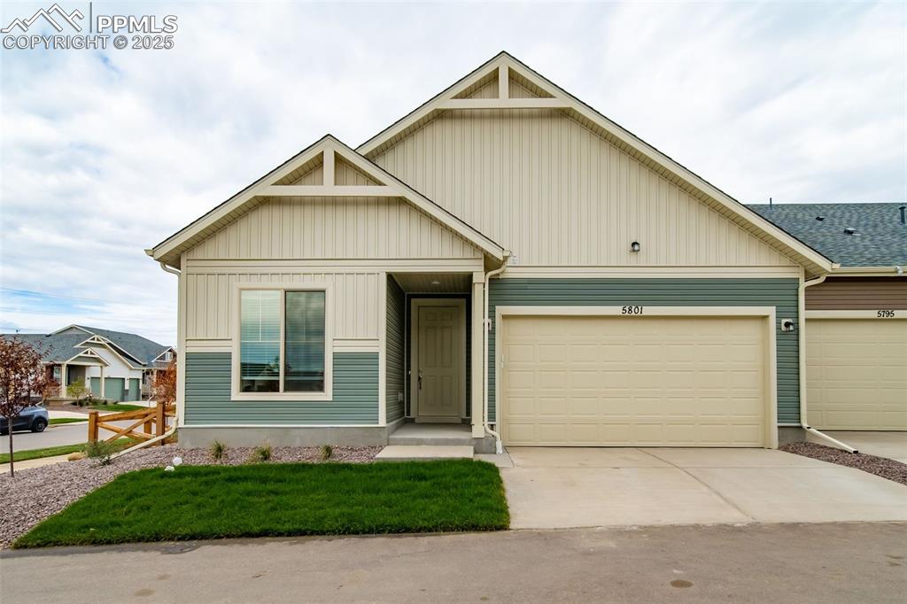 Caption: View of front of property featuring concrete driveway, a garage, a front lawn, and board and batten 