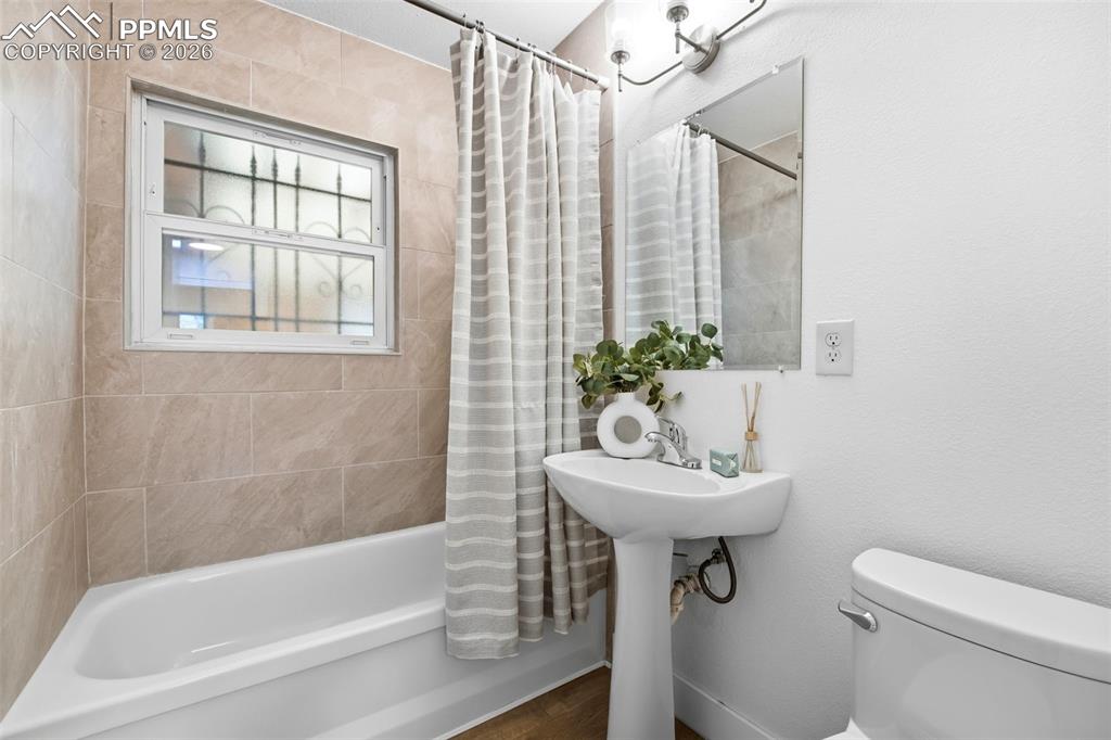 Image 12 of 38: Bathroom featuring a white pedestal sink, a wall-mounted mirror, and a whit