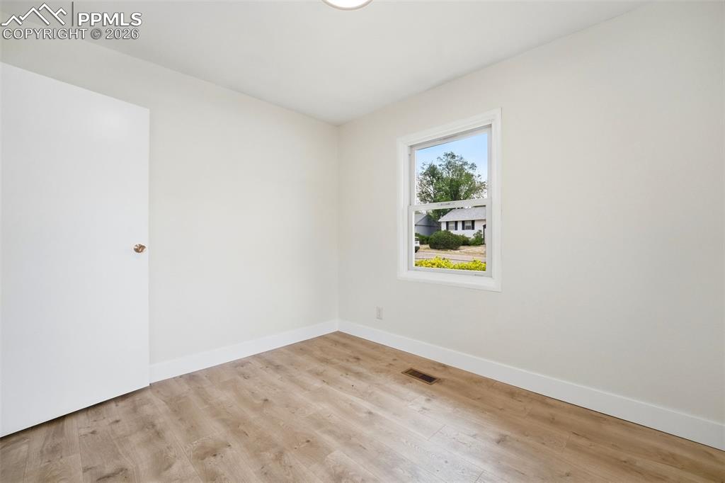 Image 15 of 38: Bright room featuring wood-finish flooring, white baseboards, a single wind