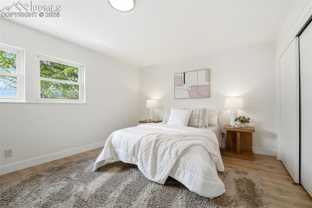Image 19 of 38: Bedroom featuring two double-hung windows, wood-finish flooring, a wall-mou