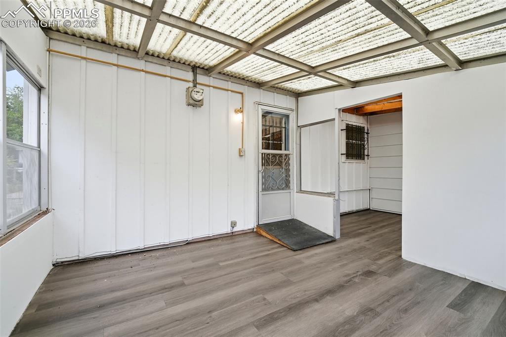 Image 24 of 38: Enclosed patio featuring wood-finish flooring, a transparent corrugated roo