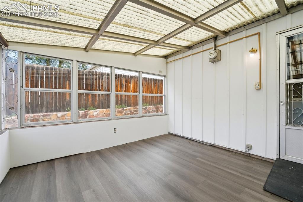 Image 25 of 38: Enclosed patio featuring wood-finish flooring, a corrugated translucent roo