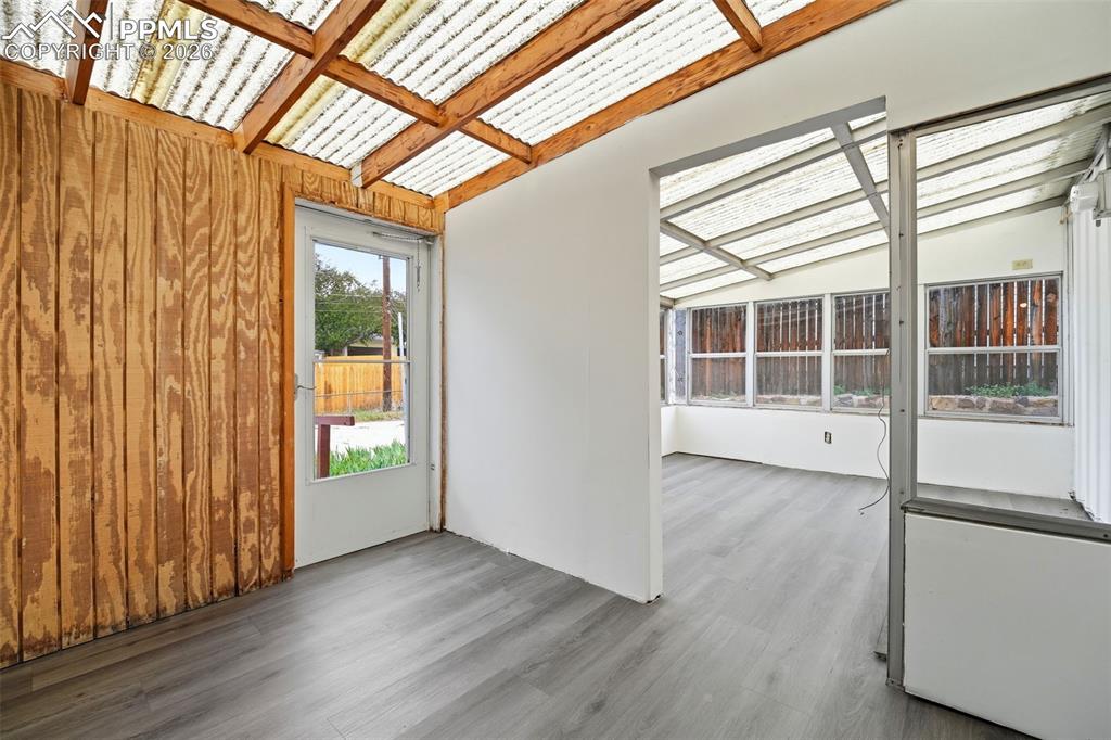 Image 27 of 38: Sunroom featuring a translucent corrugated roof, exposed wood beams, and a 