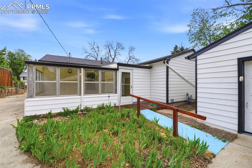 Image 28 of 38: White exterior siding with black trim, featuring a sunroom addition with mu