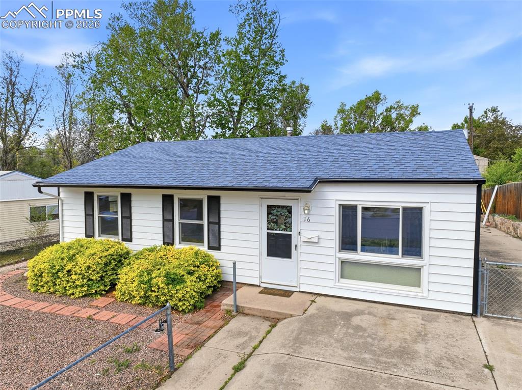 Image 30 of 38: White siding exterior with a blue shingle roof, dark gutters, and black win
